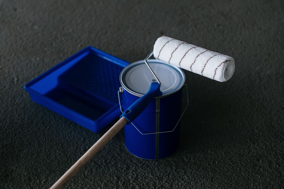 Paint roller, tray and a can of floor coating on bare concrete