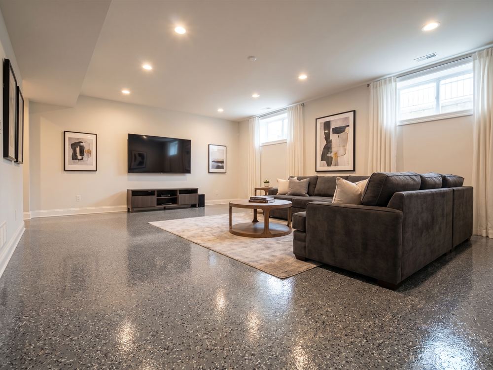 Finished basement living room with a gray flake coated concrete floor