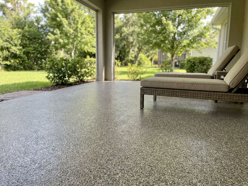 Covered patio with a flake coated concrete floor and outdoor lounge chairs